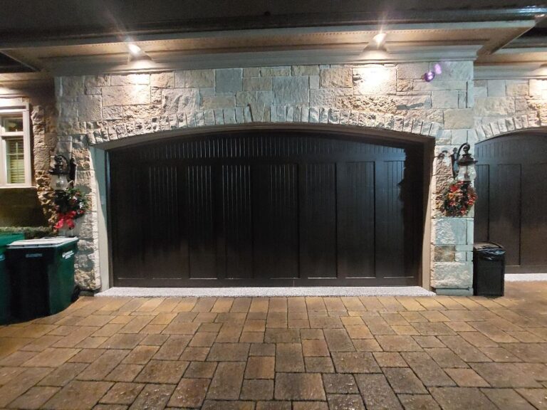 Garage door bottom seal leaking water into garage in Darien, IL: a newly installed black steel garage door with vertical