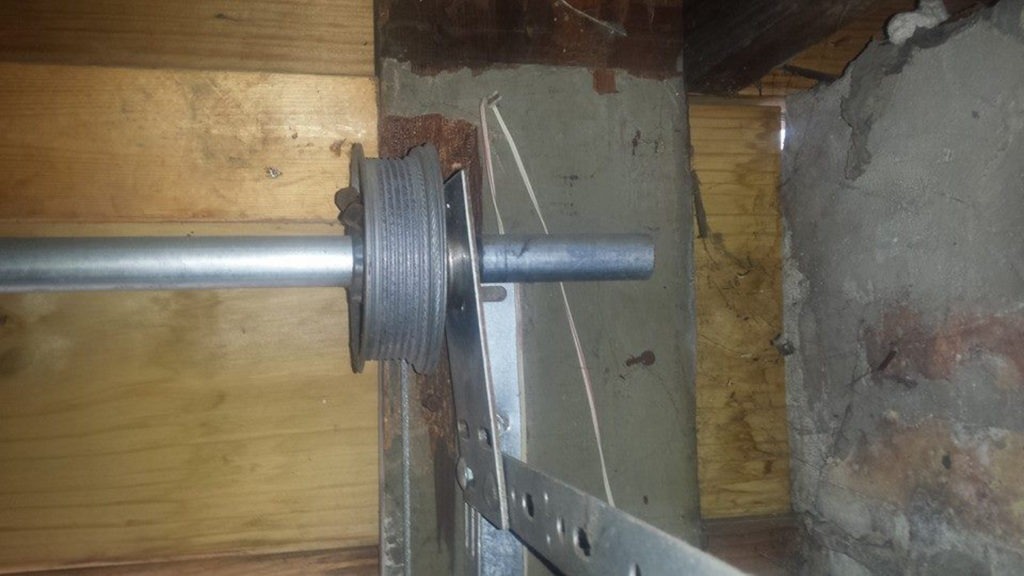Garage door spring broken in Naperville, IL: a close-up view of a garage door torsion spring assembly mounted on the header