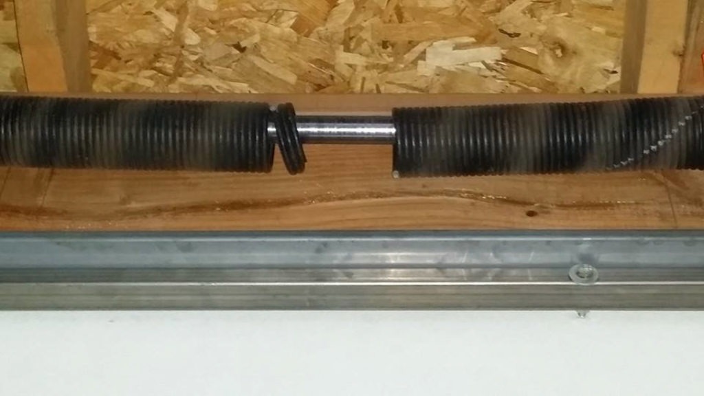 Garage door springs unbalanced causing uneven opening in Geneva, IL: a torsion spring assembly mounted above a garage door