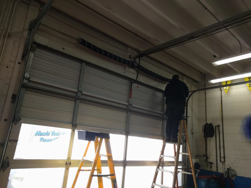 Garage door track misaligned causing grinding noise in Glen Ellyn, IL: a technician standing on a ladder installing